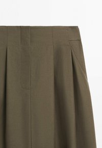 Olivengrøn plisseret nederdel med bred taljebånd og diskret syningsdetalje på glat stof.