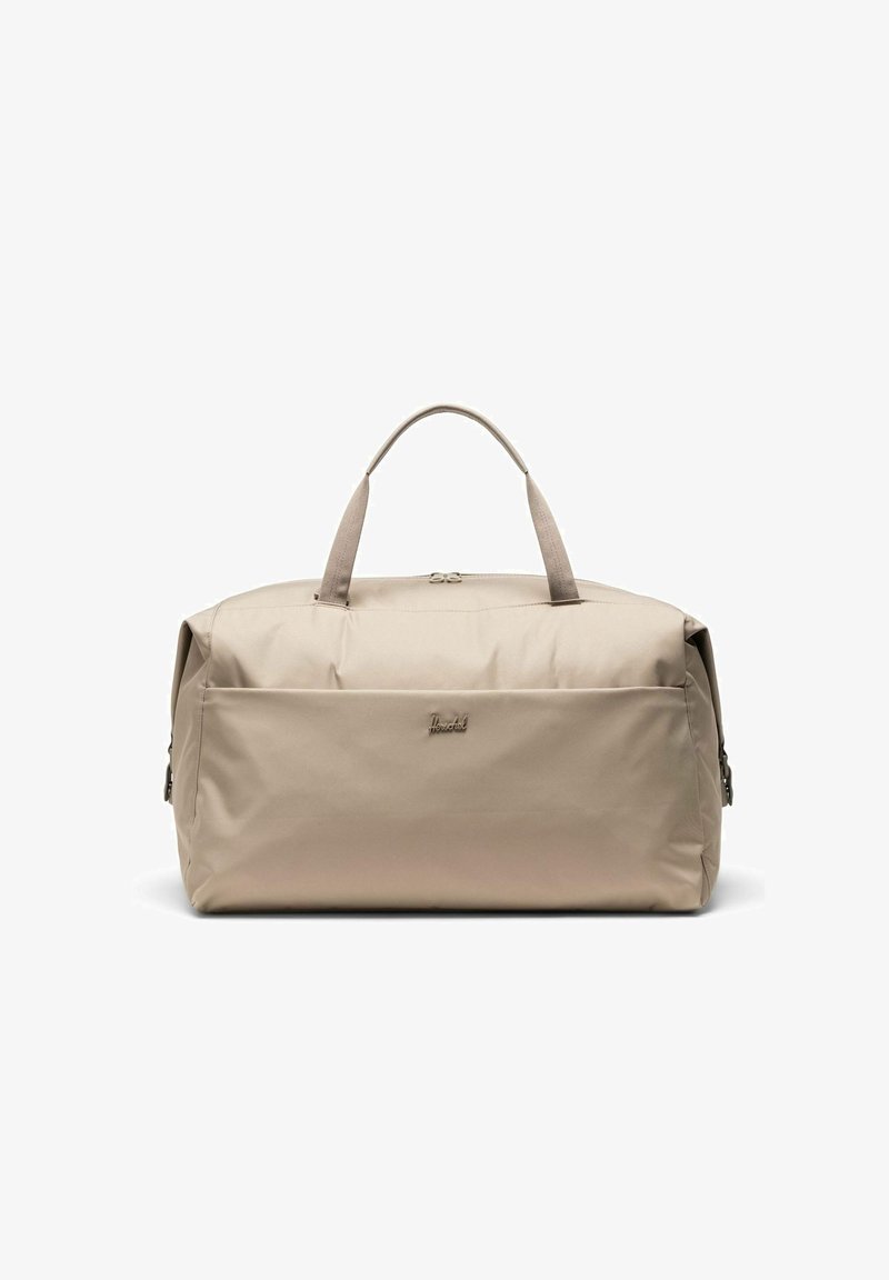 Sac de sport rectangulaire beige avec double poignées, poche avant zippée et logo de marque discret sur une surface en tissu lisse.