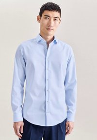 Lichtblauw overhemd met lange mouwen, gemaakt van katoen, met een puntige kraag, knoopsluiting aan de voorkant en een klassieke pasvorm, zonder zichtbare patronen.