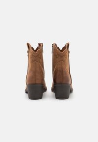 Brązowe skórzane botki za kostkę z fakturowanym wykończeniem, zamkiem błyskawicznym i falistym wzorem na górze, wyposażone w obcas typu słupek i delikatne detale przeszyć.