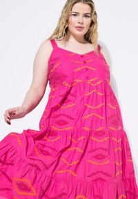 Fuchsia Baumwoll-Maxikleid mit Spaghetti-Trägern, das orangefarbenen geometrischen Stickereien und Knöpfen, einem gestuften Design und einer ausgestellten Silhouette präsentiert.