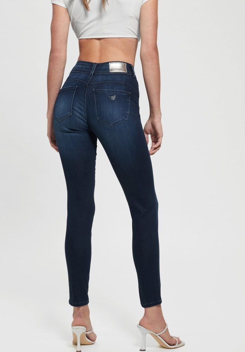 Schmal geschnittene dunkelblaue Denim-Jeans mit mittlerer Taille, ausgestattet mit zwei Gesäßtaschen und einem Logotag am Bund.
