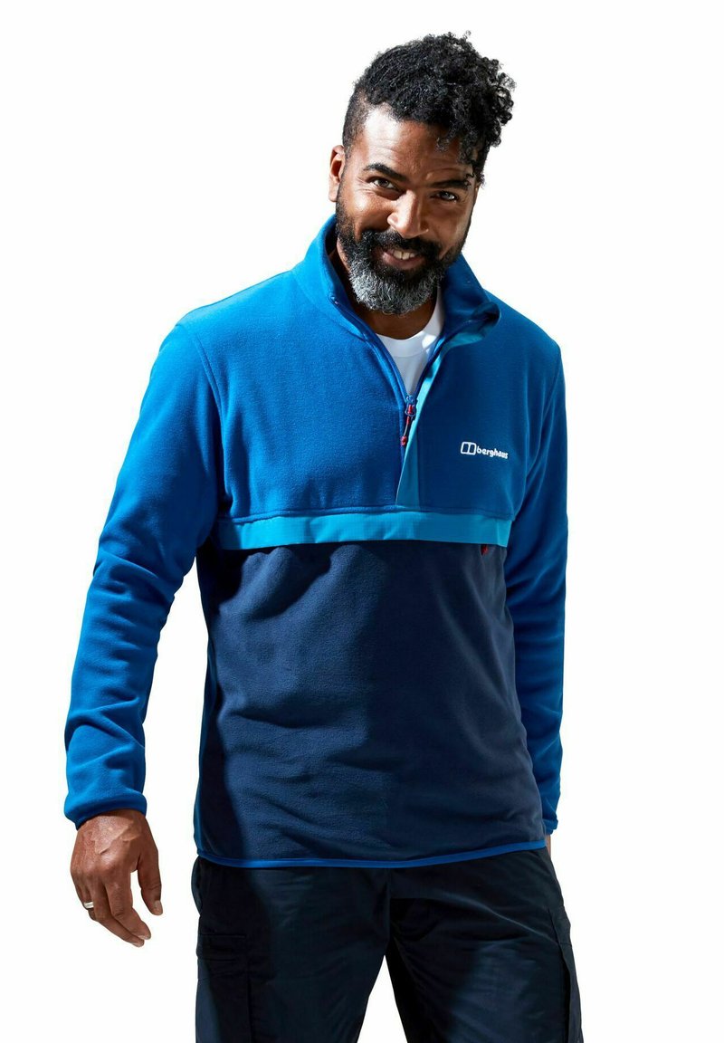 Blauwe fleece pullover met een kwartrits, contrasterende lichtblauwe horizontale band en elastische manchetten. Voorzien van een logo op de linkerborst.
