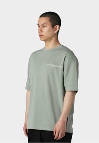 Grøn oversized T-shirt med korte ærmer, lavet af blødt stof. Har logo tekst på brystet og en afslappet pasform.