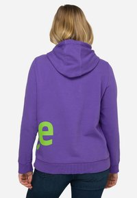 Paarse hoodie met een groene graphic op de rug, voorzien van een trekkoordkap en geribbelde manchetten, gemaakt van zachte, gestructureerde stof.