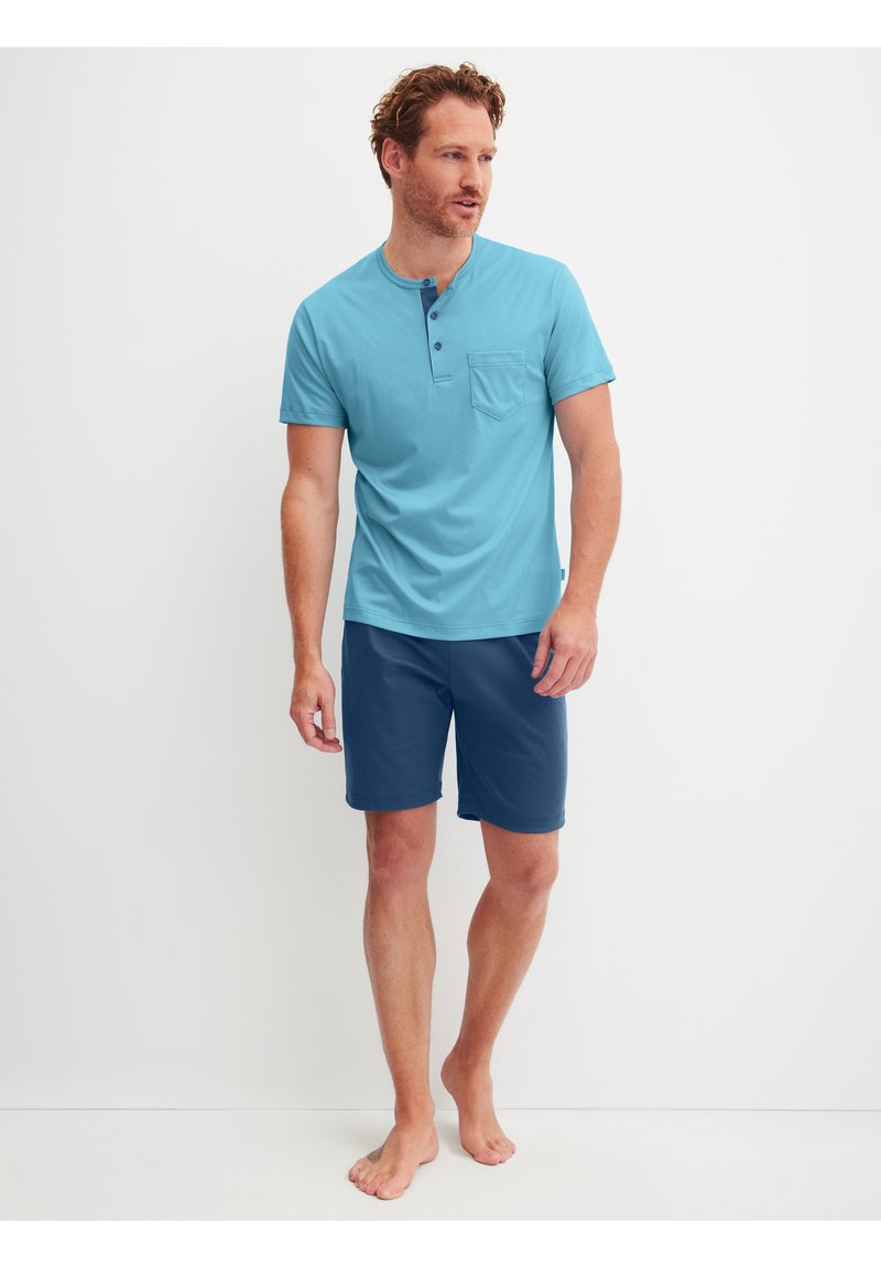Chemise henley à manches courtes bleu clair avec une poche poitrine, associée à un short bleu foncé. Tissu doux, coupe décontractée et design simple.
