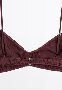 Bralette en tissu bordeaux avec des bretelles réglables, une finition lisse et un léger rembourrage, agrémenté de couture décorative et d'un fermoir en métal dans le dos.
