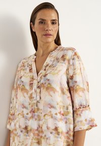 Leichtes, blumengemustertes Blusenshirt in Pastellfarben, mit einem V-Ausschnitt und Rüschen, dreiviertellangen Ärmeln mit Rüschensaum und Knopfdetails.