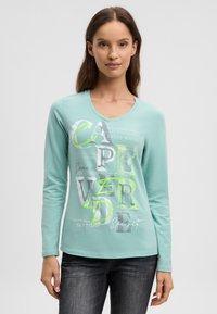 Hellblaues Langarmshirt mit V-Ausschnitt, das gemischte Typografie in Grün und Grau zeigt und einen leicht geschwungenen Saum hat.