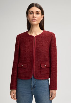 Rote Tweedjacke mit rundem Hals, sichtbarem Frontreißverschluss und zwei aufgesetzten Fronttaschen, versehen mit silberfarbenen Knopfakzenten.