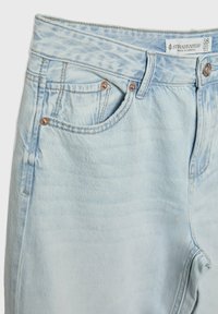 Hellblaue Denim-Jeans mit Fronttaschen, Kupfernieten, Gürtelschlaufen und einem Stradivarius Markenetikett im Taillenbund.