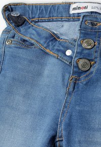 Jeans de denim en un color azul clásico. Las características incluyen un cierre de cremallera, cuatro botones y costuras en contraste. Fabricados con un tejido suave para mayor comodidad.