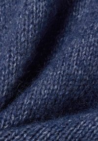 Granatowy, dziany materiał o miękkiej, teksturowanej powierzchni, z widocznymi, plecionymi wzorami i delikatnym puszkiem, które wskazują na ciepło.