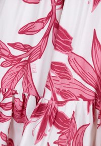 White fabric with pink floral patterns and gathered stitching creating a tiered design on the cloth.