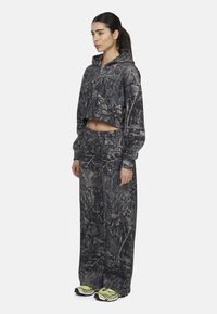 Felpa con cappuccio accorciata e pantaloni a vestibilità comoda in un motivo camouflage scuro. Il tessuto ha una consistenza morbida, con polsini e vita elasticizzati.