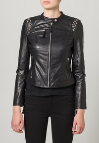 Černá kožená bunda s přiléhavým střihem, kovové cvočky na ramenou, přední zip a zipové boční kapsy, a žebrovaný lem.