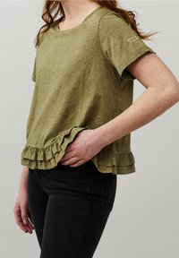 Olivgrön kortärmad skjorta med avslappnad passform och volangnedtill. Tyget är texturerat, lätt och har subtila sömdetaljer på ärmen.