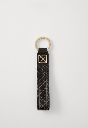 Schwarzer Leder-Schlüsselanhänger mit geprägt geometrischem Muster, goldfarbener Hardware und einem runden Schlüsselring zur Befestigung, mit einem dekorativen quadratischen Akzent.