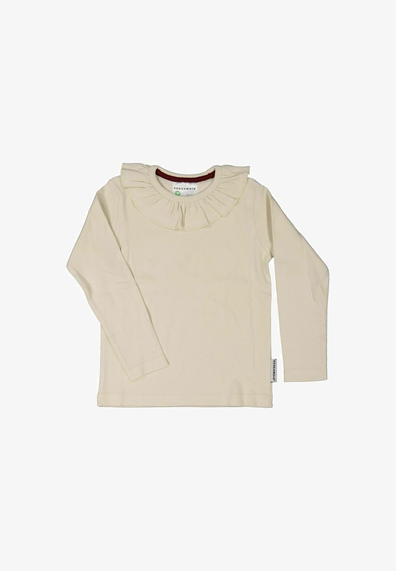 Långärmad ljusbeige topp med ribbad yta och en fladdrande krage. Etikett på sidan visar varumärket. Avslappnad design.