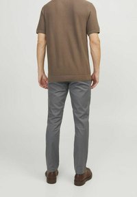 Suéter marrón de manga corta con tejido texturizado, combinado con pantalones gris de corte slim, completado con zapatos marrones. Vista trasera.