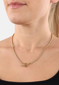 Guld- och silvervirad kedjehalsband med en rund lås, som har släta metalldetaljer och en flätad textur.