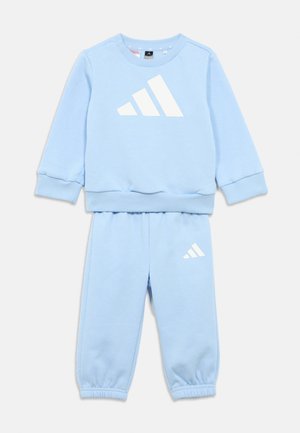 Svetlomodrá bavlnená mikina a zodpovedajúce športové nohavice s bielymi akcentmi loga Adidas. Rebrované manžety a pás, neformálny dizajn.