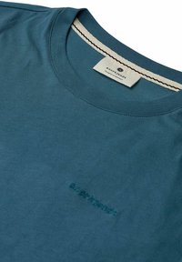 Tricou de bumbac cu mânecă scurtă, de culoare teal, cu guler rotund, textură subtilă și nume de marcă brodat în aceeași nuanță.