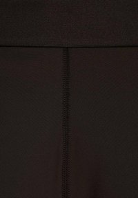 Leggings sportivi neri con una texture liscia, cintura ampia e cuciture rinforzate lungo la cucitura centrale.