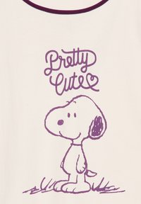 White t-shirt with purple neckline, featuring a graphic of Snoopy standing on grass and the text "Pretty Cute" in a playful font.