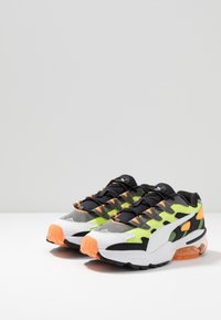 Sneakers med en överdel i nät i grått och neongrönt, svarta accenter, orange häl och sula, med svarta snören och vadderad krage.