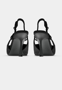 Μαύρα σανδάλια με ψηλό τακούνι και ανοιχτή πλάτη, με κομψό σχεδιασμό, λεπτά λουράκια και μυτερό τακούνι στιλέτο για μια κομψή σιλουέτα.