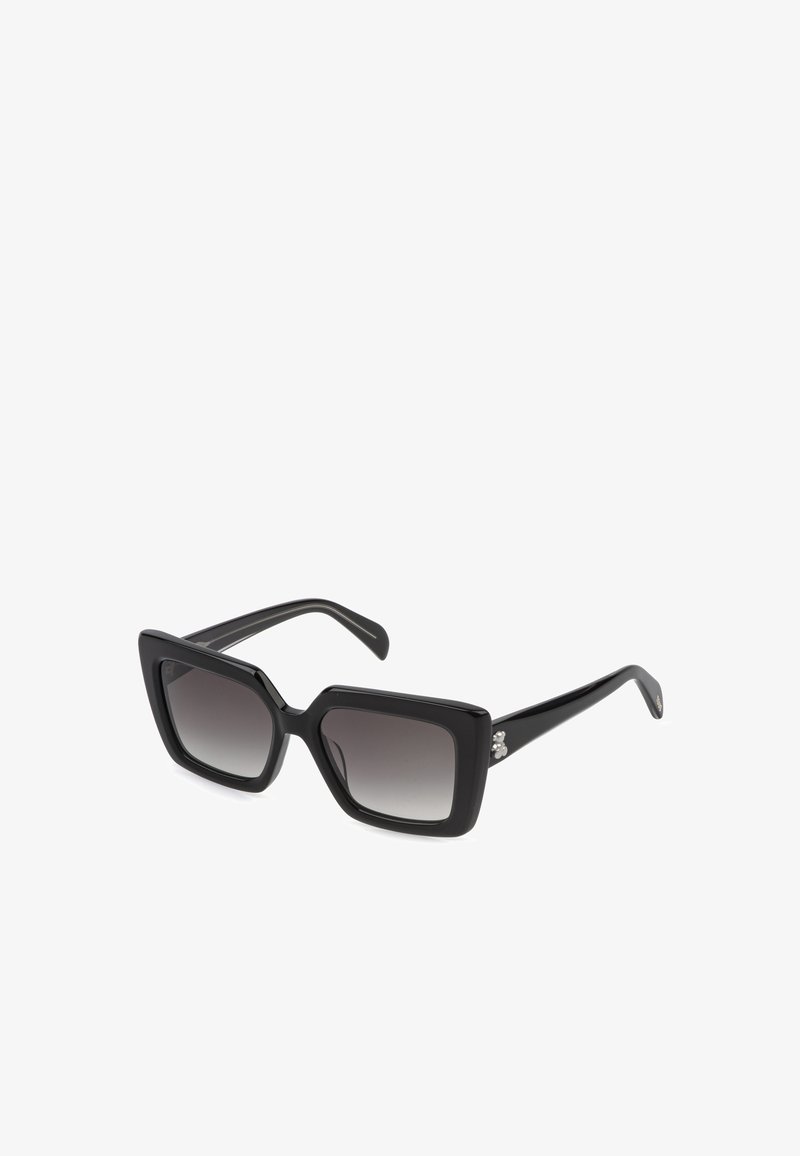 Lunettes de soleil rectangulaires noires avec une monture épaisse et des verres dégradés foncés, inclinées vers la droite sur un fond blanc.