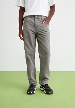 Gray denim pants with a straight-leg design, featuring front pockets and a button closure, paired with black athletic shoes.