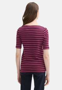 Mørkerød T-shirt med vandrette lyserøde striber, glat tekstur, korte ærmer og en bred halsudskæring. Bært med mørk denim jeans.
