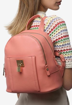 Piccola borsa zaino in pelle rosa con due cerniere, tasca frontale con dettaglio della chiusura dorata e doppio manico superiore per il trasporto.