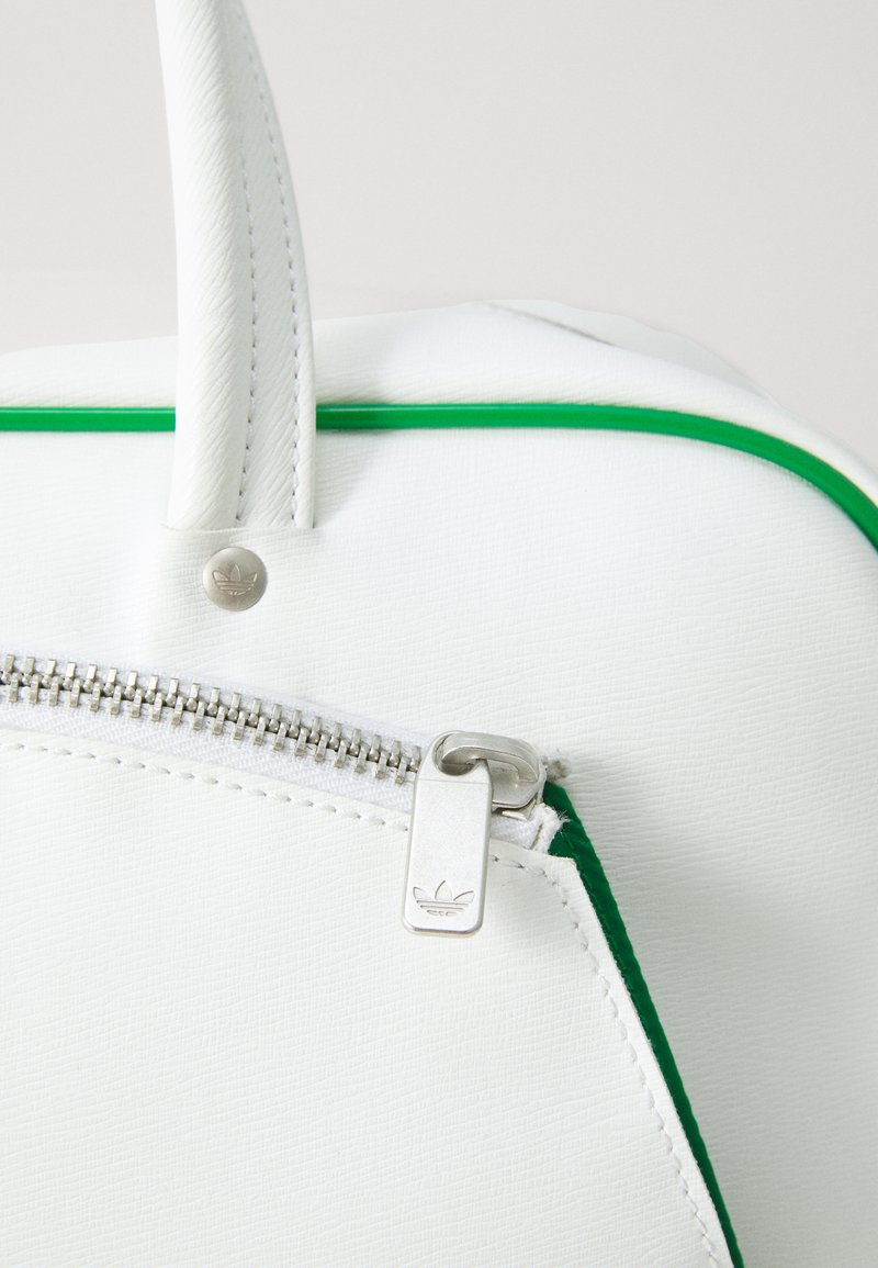 White bag with green accents, smooth synthetic material, top zipper with silver hardware, and stitching details on the edges.