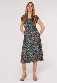 Un vestido floral con un bodice ajustado y mangas cortas, que presenta un fondo verde oscuro y flores multicolores. De longitud media con una silueta fluida.