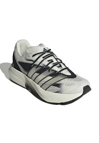 Lätta sneakers i vitt och svart mesh med strukturerad ovandel, kontrasterande svarta ränder och en vadderad sula märkt "LIGHTSTRIKE".