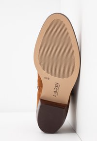 Brown suede shoe with a rounded toe, featuring a textured sole and a brown wooden heel. Size label reads 6.5 B.
