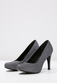 Chaussures à talons hauts grises avec un dessus texturé arborant un motif en losange et un intérieur noir lisse, design à bout pointu et talon aiguille fin.
