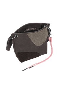 Bolsa de tela marrón con una correa rosa y parches de texturas variadas en marrón oscuro y gris. El interior forrado presenta un patrón de lunares rosas.