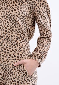 Mikina s leopardím potiskem v béžové tkanině, s kulatým výstřihem, dlouhými rukávy a volným střihem, která má boční kapsu.