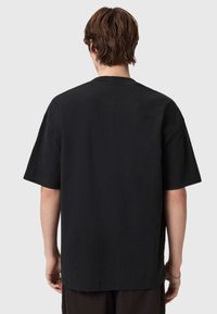 Μαύρο βαμβακερό μπλουζάκι με κοντά μανίκια και χαλαρή εφαρμογή, διαθέτει στρογγυλή λαιμόκοψη και απλή υφή. Χωρίς ορατά λογότυπα ή σχέδια.