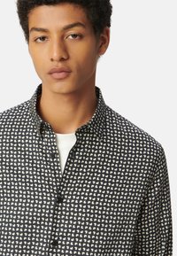 Camicia con bottoni nera con un motivo astratto bianco. Presenta un colletto classico e una trama di tessuto liscia. Due bottoni visibili al collo.