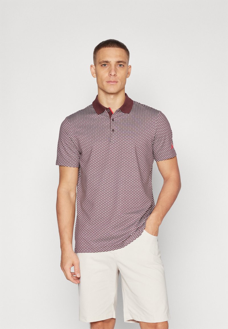 Polo triko s vínovým a bílým vzorem, s vínovým límečkem. Krátké rukávy a slim fit, v kombinaci s bledě béžovými šortkami.