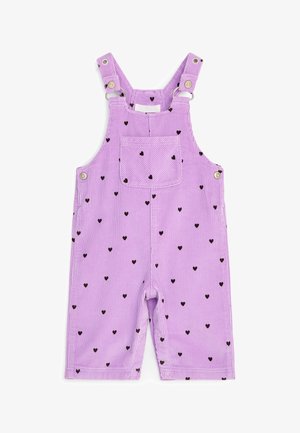 Salopette en velours côtelé lilas pour enfant avec motifs de cœurs noirs, poche avant, bretelles réglables et boutons-pression sur les côtés et à l’entrejambe.
