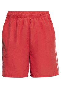 Red athletic shorts made of lightweight fabric, featuring an elastic waistband, side pockets, and white stripes along the sides.