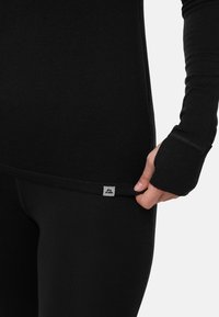 Svart långärmad topp och tajta leggings i ett mjukt, stretchigt tyg. Har tumöglor i ärmarna och en liten logotypetikett vid fållen.