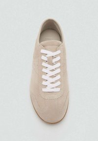 Beige suede tenisice s okruglim vrhom, bijelim vezicama i gumenim potplatima. Sadrži tonirane šavove i minimalno brendiranje na jeziku.