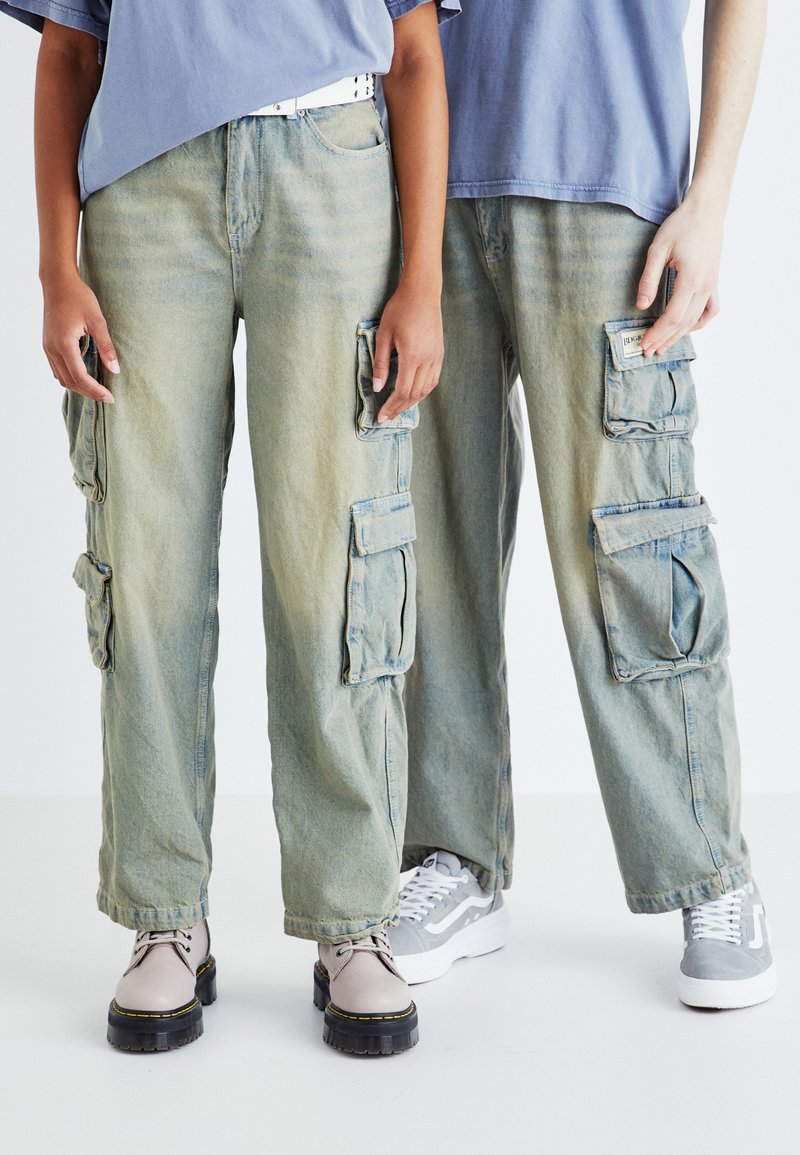Cargo bukser i falmet lyseblå denim med flere lommer. Løs pasform, lige bendesign, med en tekstureret finish og justerbare manchetter.